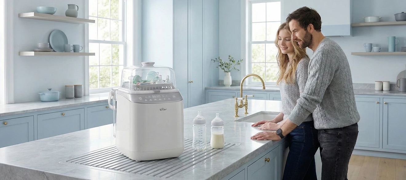 Bear Bottle Washer Pro baby bottle washer on a modern kitchen island with baby bottles and parents in the background.
