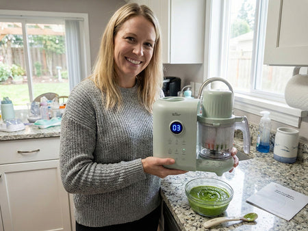 Smiling mother taking a baby bottle from the digital Bear Baby Bottle Warmer on a granite kitchen counter.