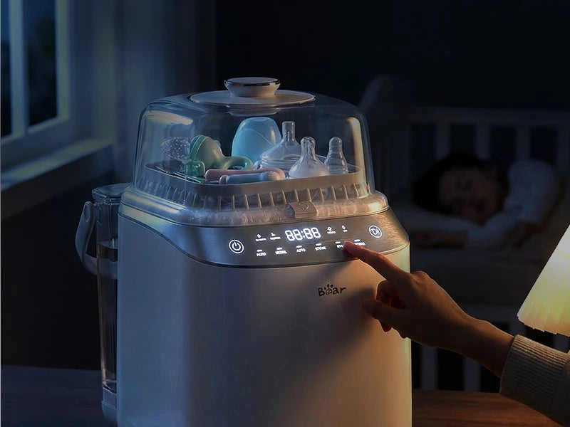 Bear Bottle Washer Pro used at night with illuminated touch controls and a sleeping baby in the background.