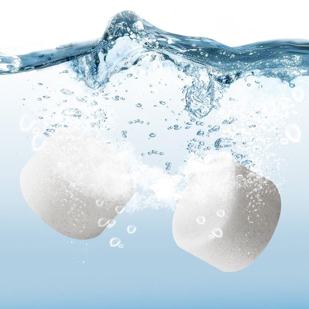 Two white Bear Detergent Tablets rapidly dissolving and effervescing in clean water.