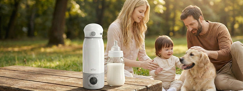 Family and dog relaxing outdoors by a Bear Portable Bottle Warmer for Travel on a picnic table.