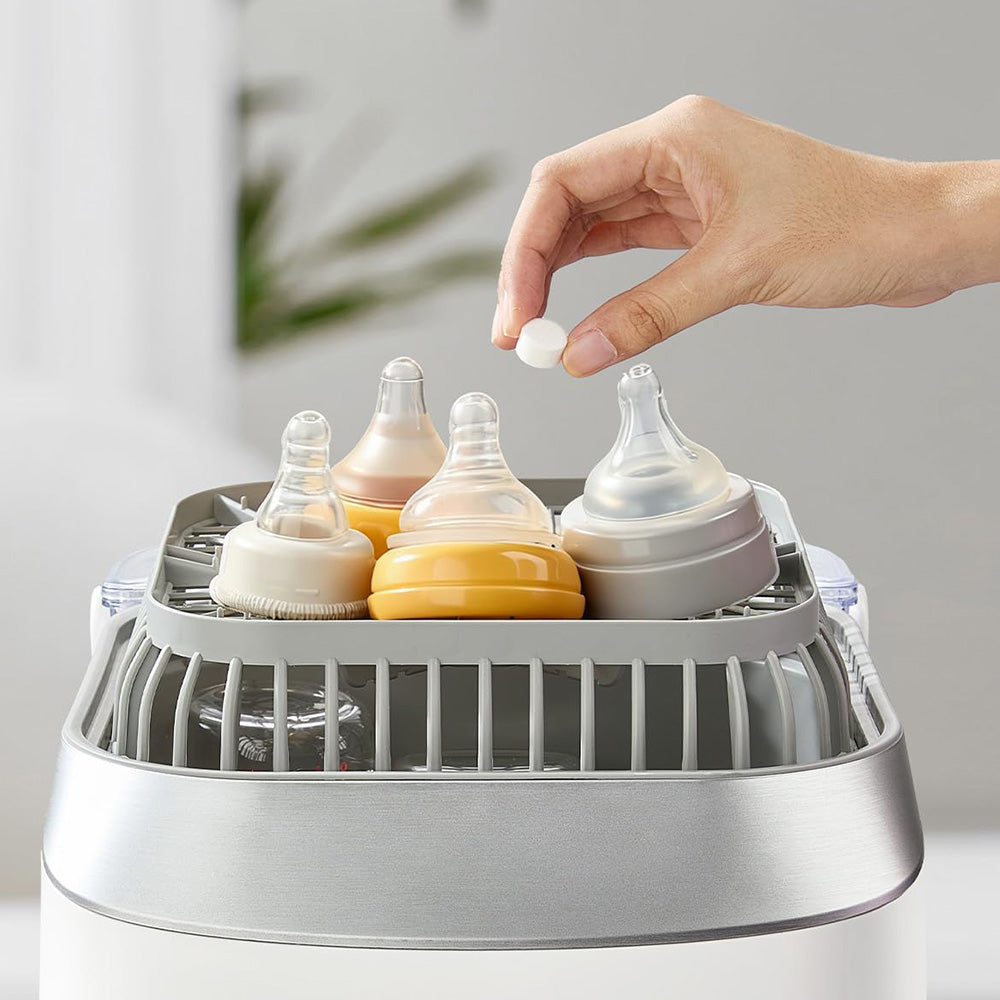 Hand placing a Bear Detergent Tablet into the accessory rack of an automatic bottle washer.